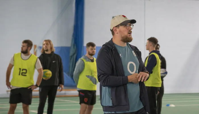 A sports coach leading a session with students.