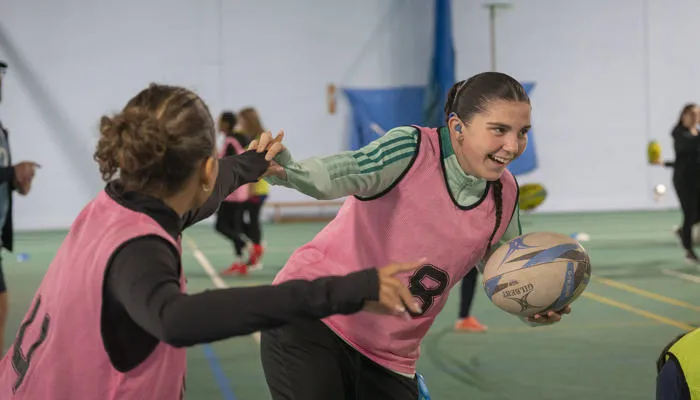 Students playing touch rugby inside the tennis hall.