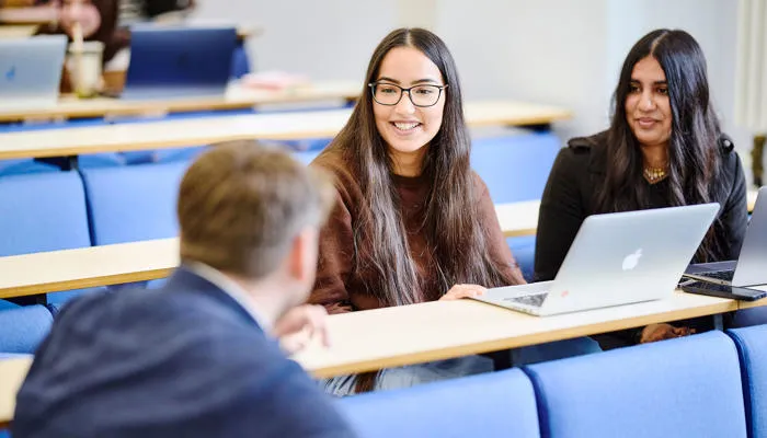 group of students smiling around laptop