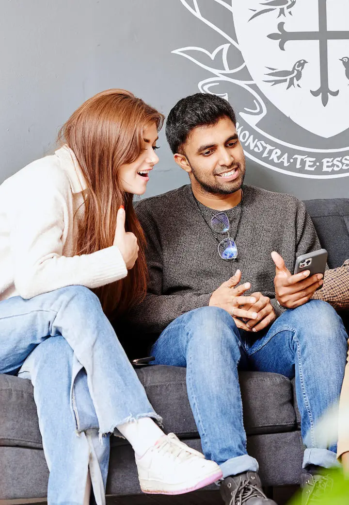 students chatting looking at phone on couch
