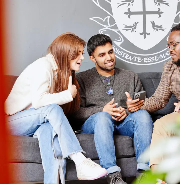 students chatting looking at phone on couch