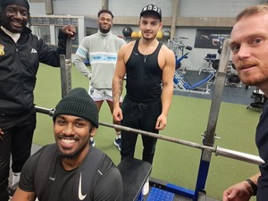 Students surrounding a gym bench smiling for a photo.